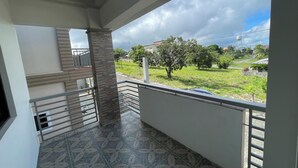 A balcony with a patterned floor, a railing, and a view of a green landscape with trees and a water tower. - Serene 7-Bedroom Retreat House near Attractions and Dining Tagayay (Tagaytay City)
