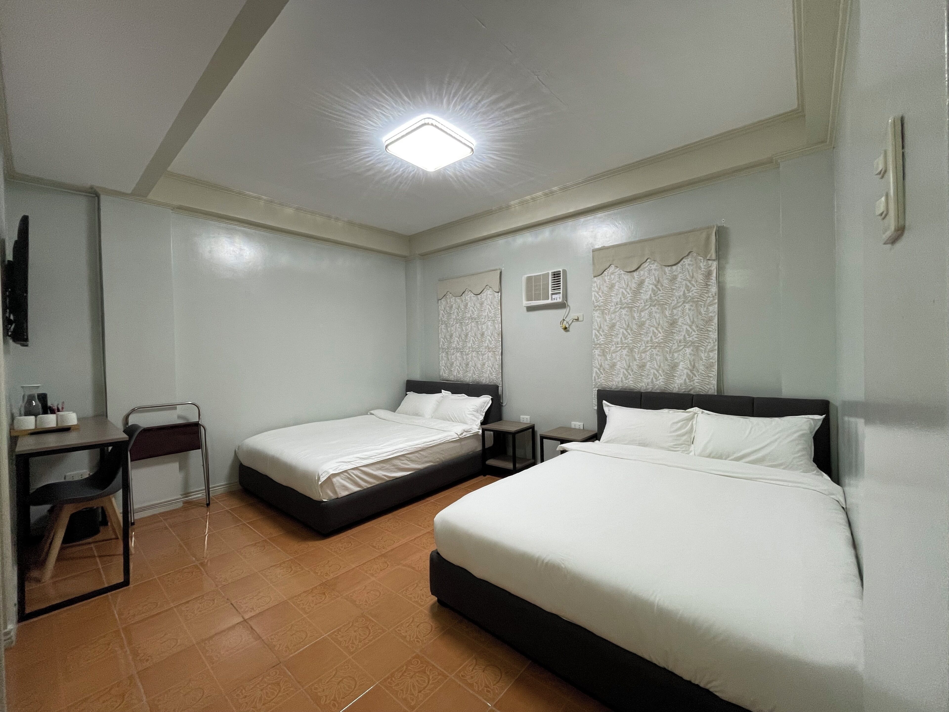 A hotel room with two beds, a desk, and a chair.