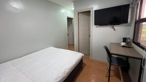 A bedroom with a bed, a desk, a chair, a television, and a door leading to another room. - Serene 7-Bedroom Retreat House near Attractions and Dining Tagayay (Tagaytay City)