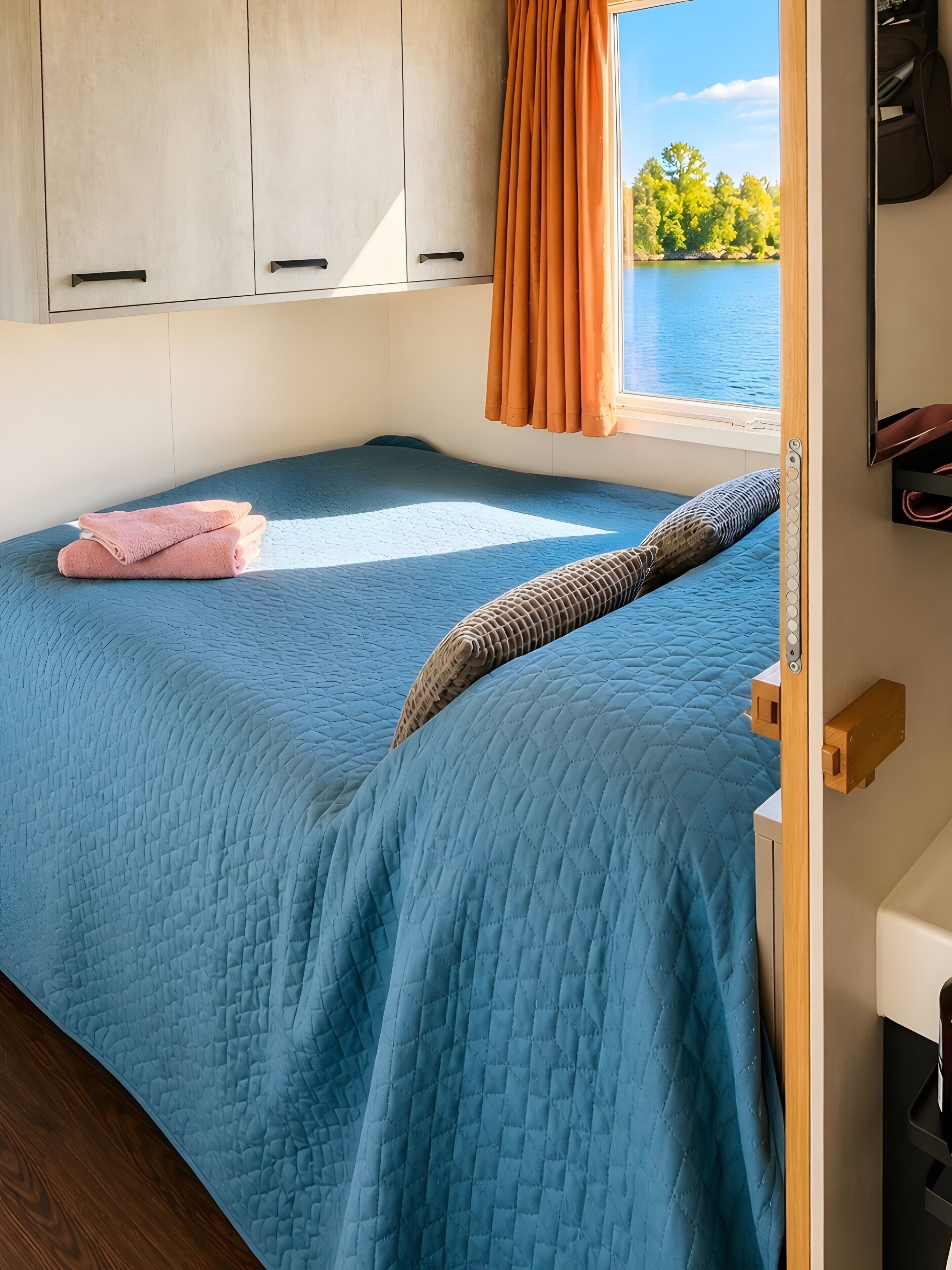 Ein Schlafzimmer mit Bett, einem Fenster mit Vorhängen und Blick auf einen See.