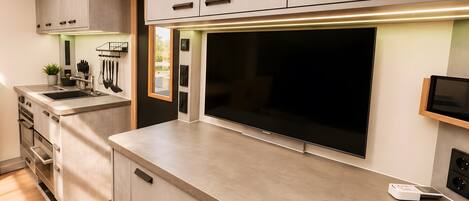 A modern kitchen with built-in appliances, a large flat-screen TV, and a minimalist design.