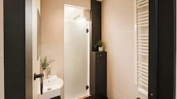 Ein modernes Badezimmer mit Duschabtrennung aus Glas, Waschbecken und Handtuchhalter.