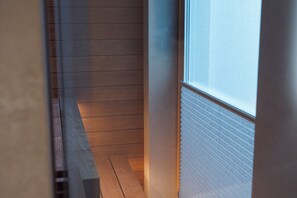 A narrow hallway with wooden flooring and a window on the right.