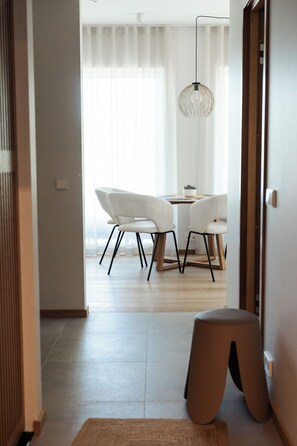 A modern interior with a dining area, a hanging light fixture, and a wooden floor.