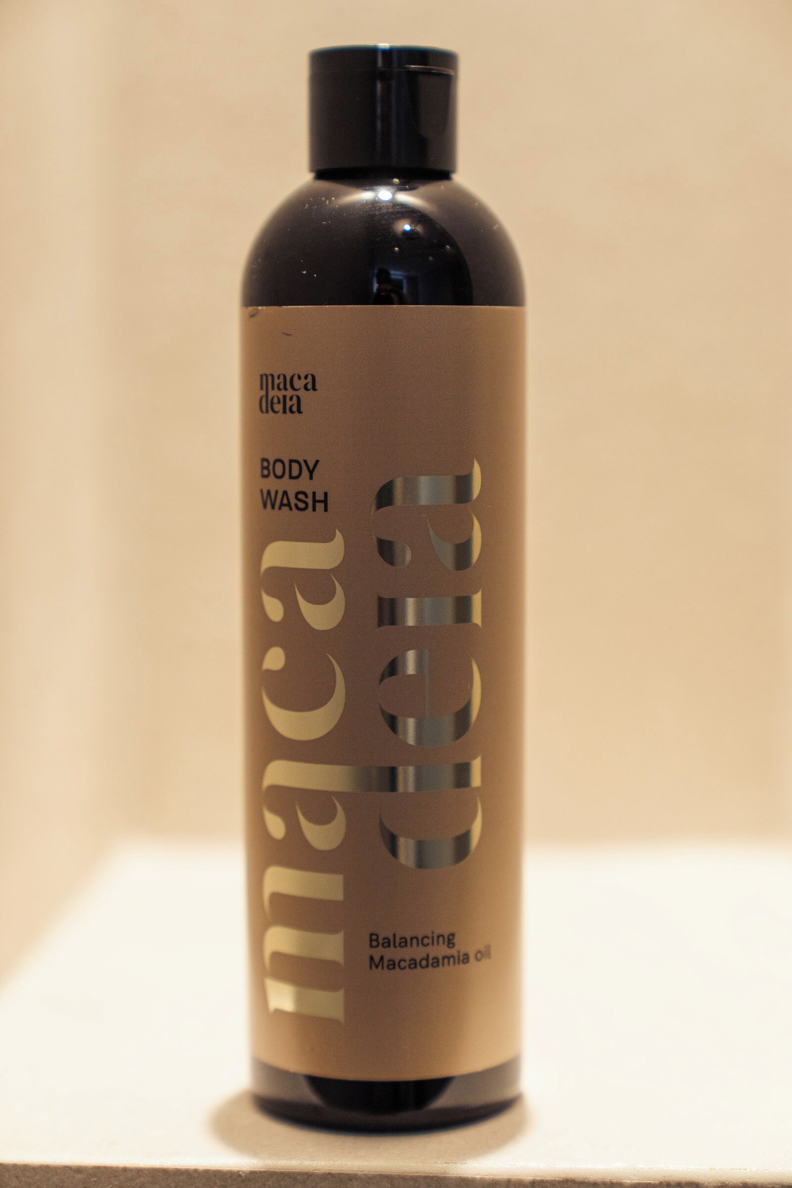 A bottle of body wash with a label that includes the text 'paca dela' and 'Balancing Macadamia oil.'