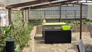 A covered outdoor area with a stone floor, a table, and a bench.
