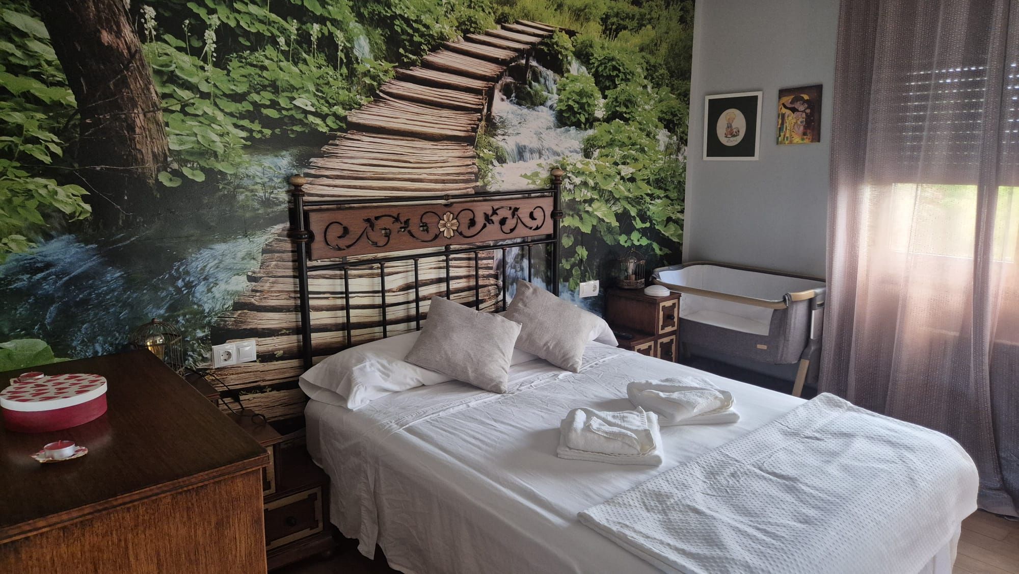 Ein Schlafzimmer mit einem Bett, Kissen, einem Nachttisch, einer Lampe und einem Wandbild.