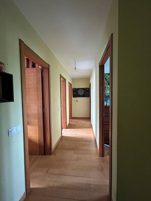 A hallway with wooden doors, a dartboard, and a light fixture.