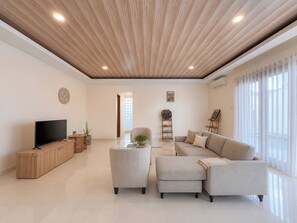 A modern living room with a flat-screen TV, a sofa set, a coffee table, and a wooden cabinet. - Villa Amaya Canggu by Nagisa Bali (Badung)