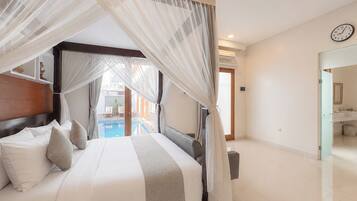 Quarto com cama de dossel, vista para uma piscina e banheiro com pia e espelho.