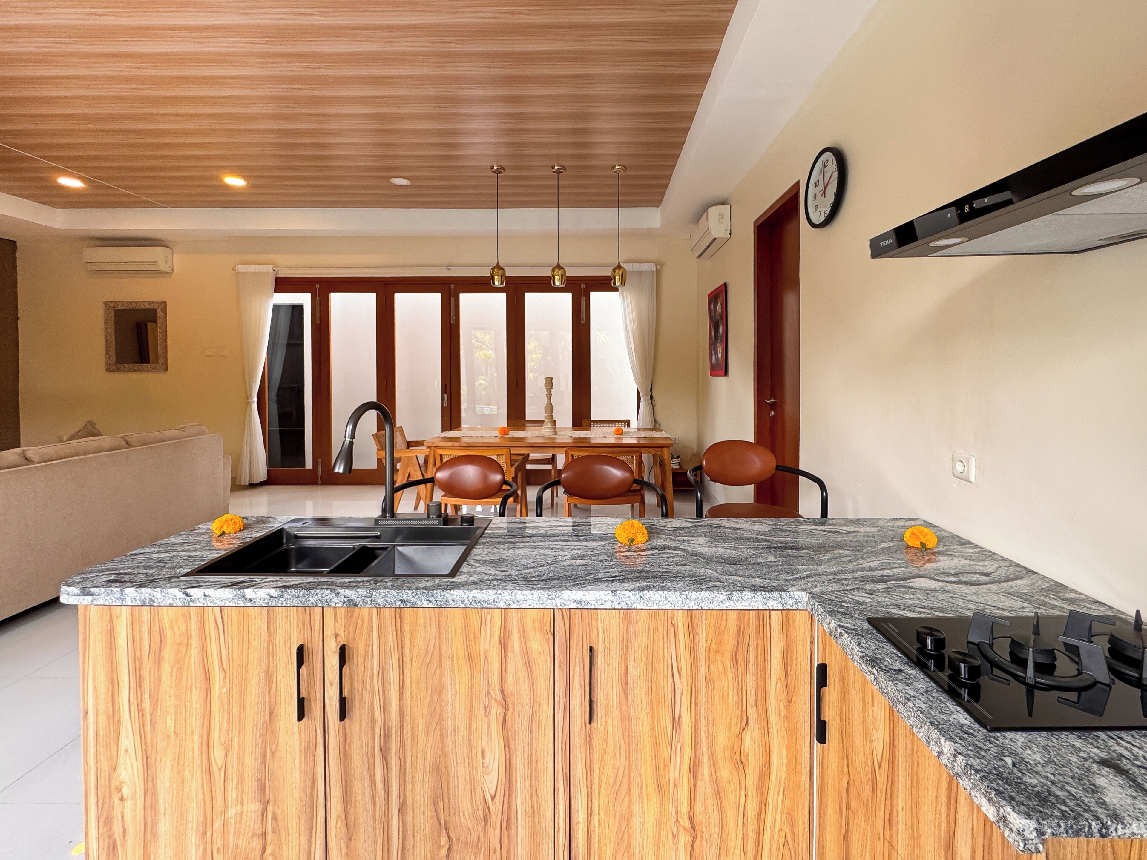 A modern kitchen with a central island, wooden cabinets, and a gas stove.