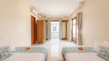 A hotel room with two beds, a balcony, and a view of the outside.