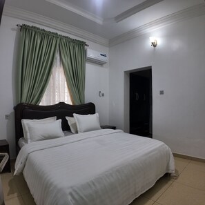 A bedroom with a bed, a nightstand, a wardrobe, and a window with curtains.