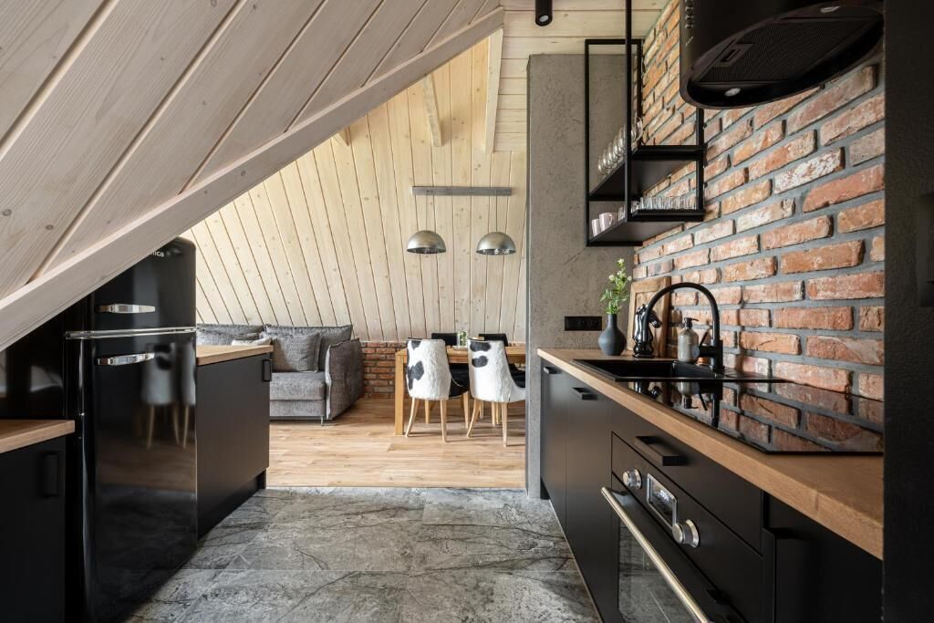 Een moderne keuken met een bakstenen muur, houten plafond en een zithoek met een bank en stoelen.