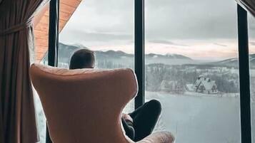 A room with a large window, a chair, and a view of a body of water.