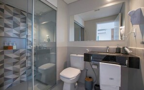 A modern bathroom with a glass shower enclosure, a toilet, a sink with a towel rack, and a mirror. - Corporate Stays First Living - 505 (Asunción)