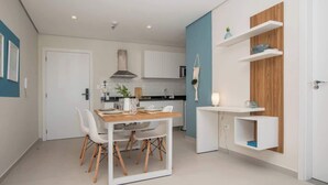 A modern kitchen with white cabinets, a wooden dining table, and white chairs. - Corporate Stays First Living - 505 (Asunción)