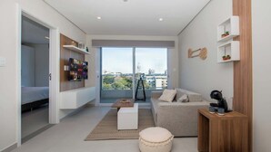 A modern living room with a sofa, coffee table, ottoman, and a TV mounted on the wall. - Corporate Stays First Living - 505 (Asunción)