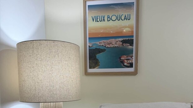Huoneessa on sohva, lamppu ja seinällä oleva kehystetty taulu.