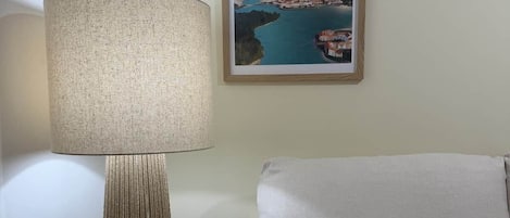 A room with a sofa, a lamp, and a framed picture on the wall.