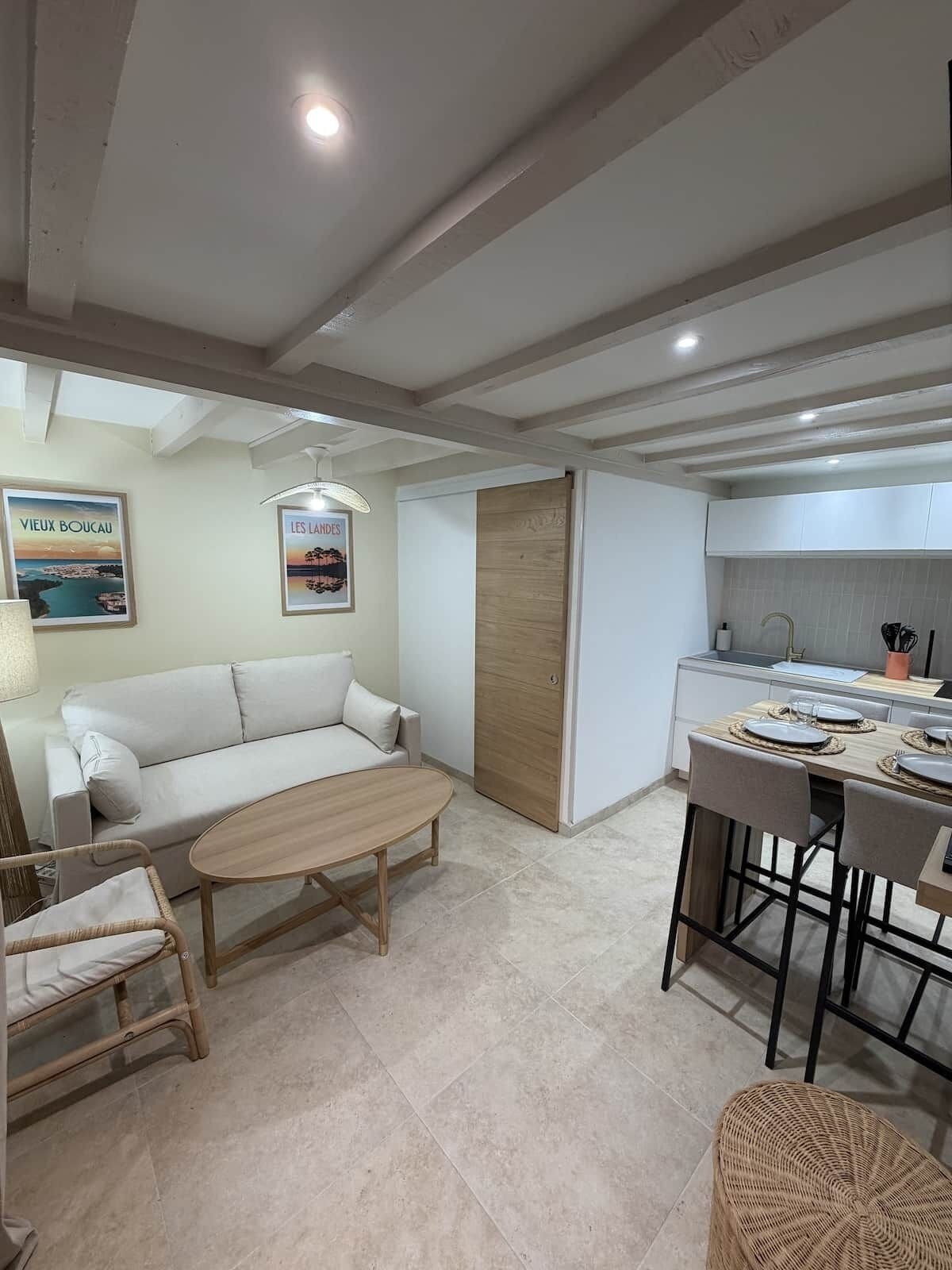 A modern living room with a sofa, a wooden coffee table, and a dining area with a table set for two.