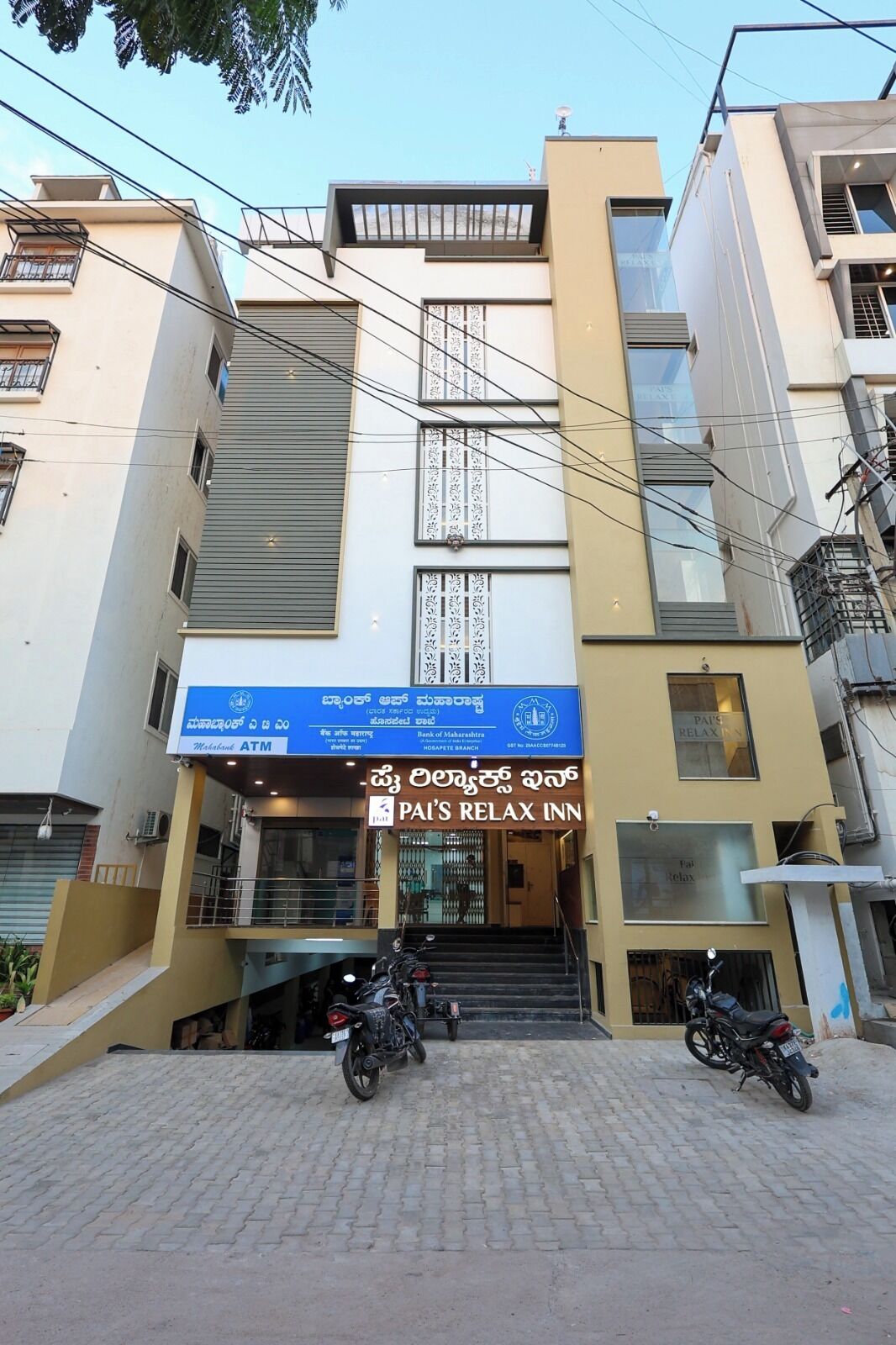 Un edificio de varios pisos con un cartel que dice 'PAI'S RELAX INN' y un cajero automático en la planta baja.