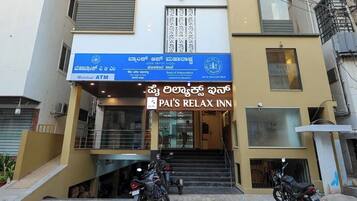 Un edificio de varios pisos con un cartel que dice 'PAI'S RELAX INN' y un cajero automático en la planta baja.