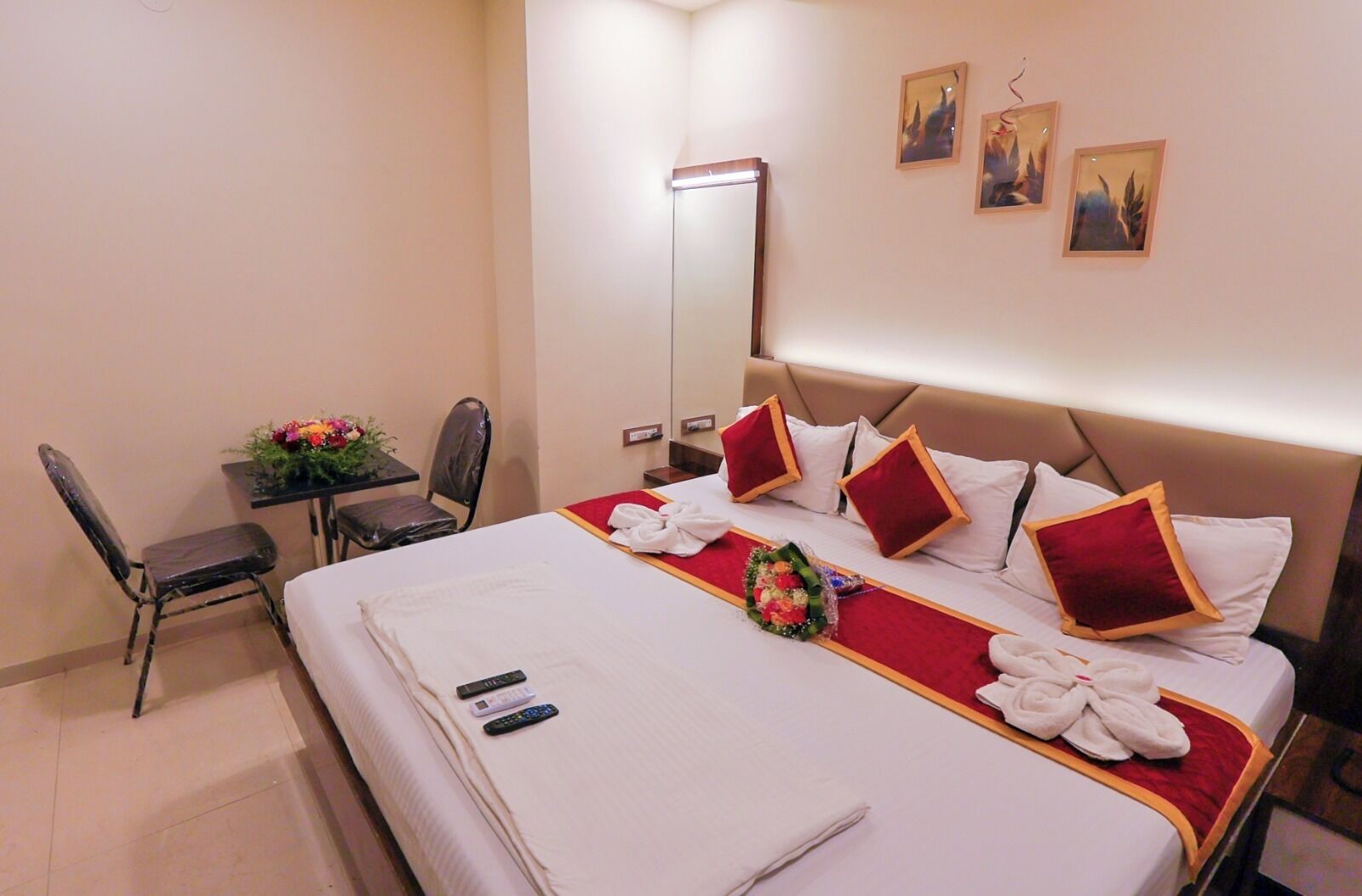 Habitación de hotel con cama, escritorio, silla, espejo y obras de arte en la pared.