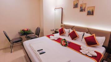 Habitación de hotel con cama, escritorio, silla, espejo y obras de arte en la pared.