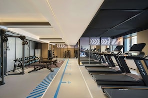 Un gimnasio con cintas de correr, mancuernas y máquinas de pesas.