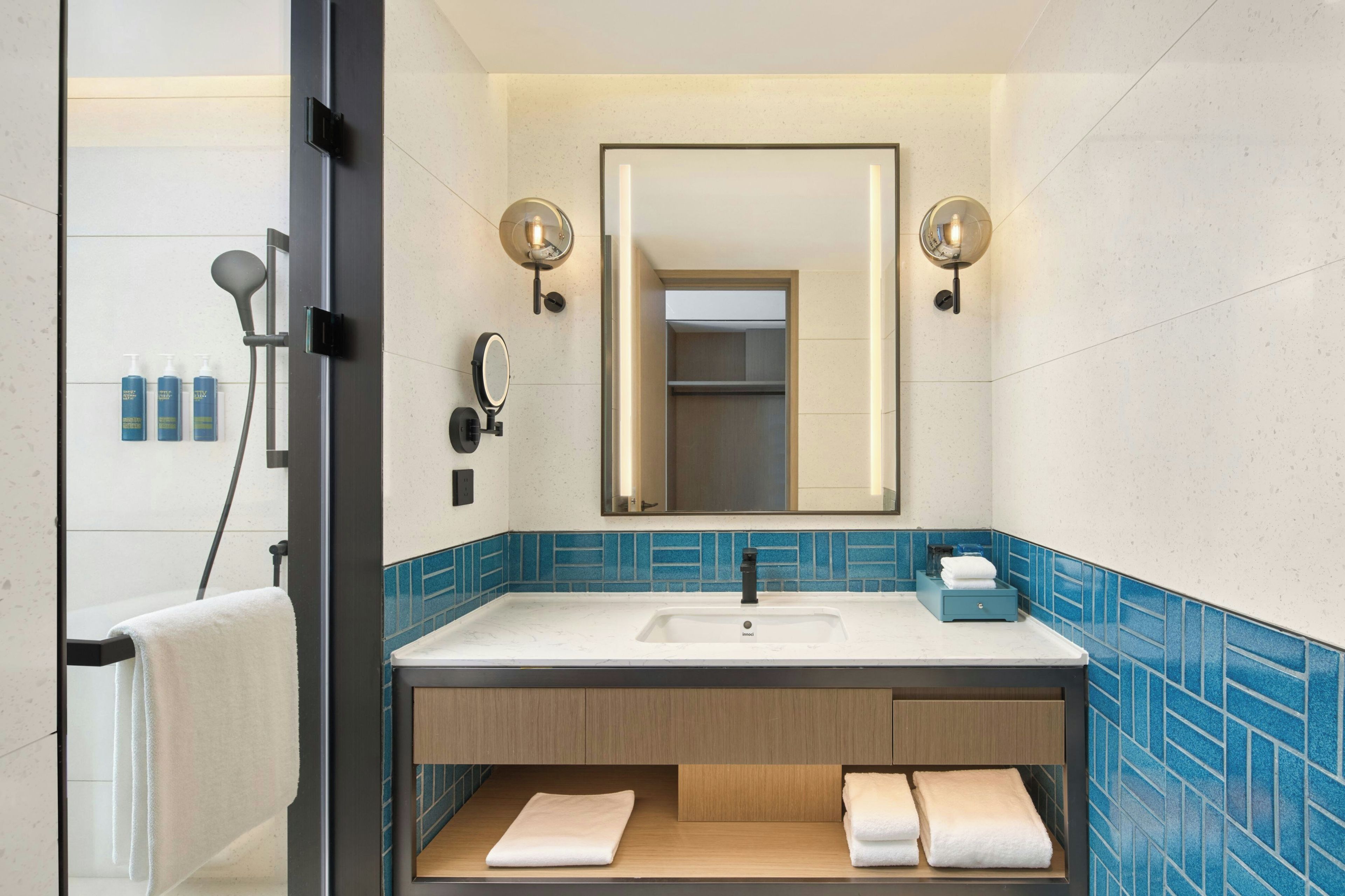Un baño moderno con un espejo grande, un lavamanos y un perchero para toallas.