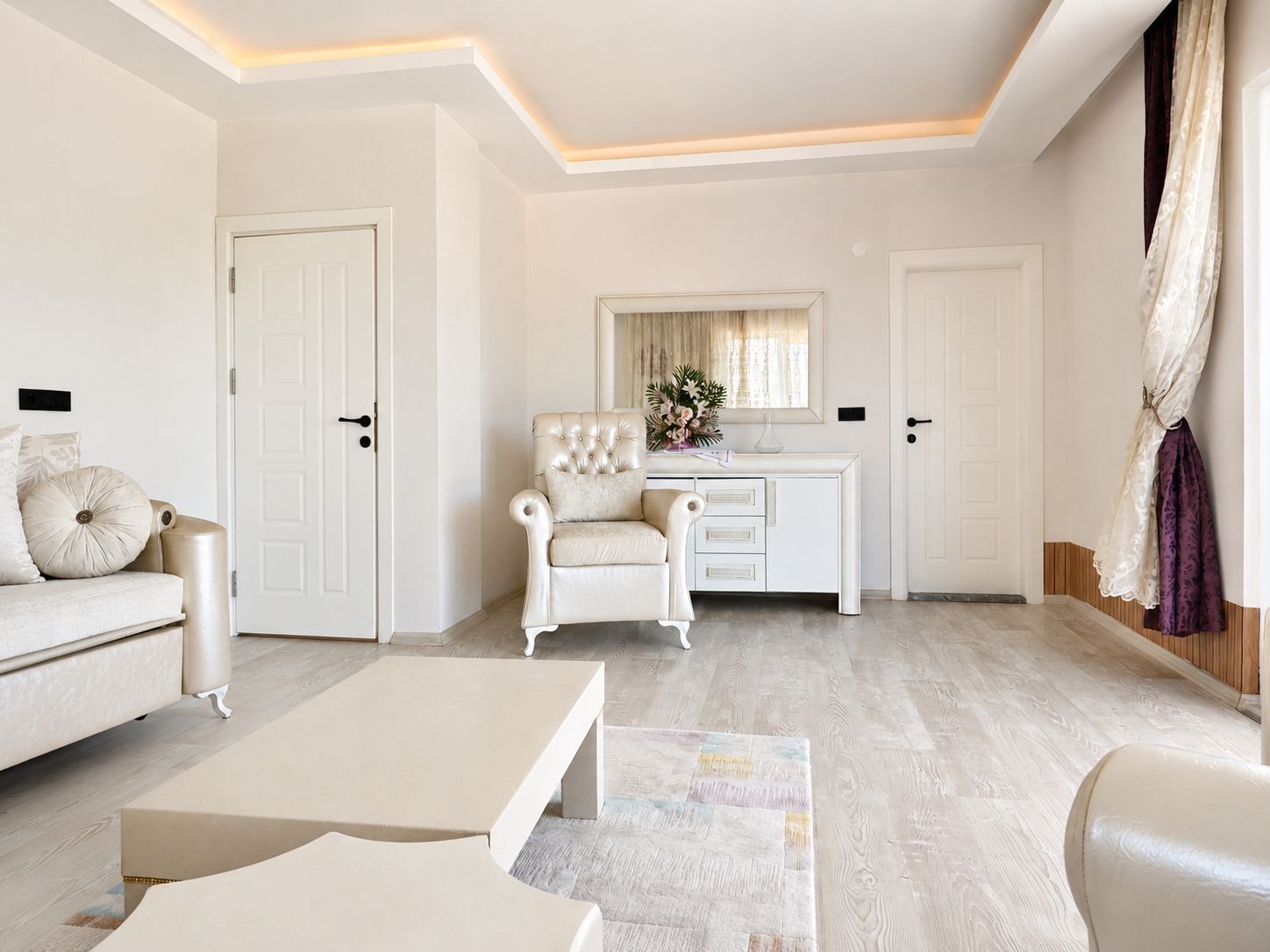 Una habitación con un sofá blanco, un sillón blanco, un escritorio blanco y una mesa de centro blanca.