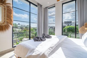 Quarto com uma cama grande, vista para o verde e edifícios, e design moderno.