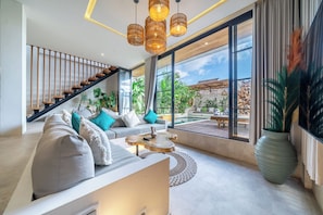 Uma sala de estar moderna com sofá, mesa de centro e vista para o exterior.