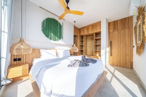 A modern bedroom with a bed, wooden wardrobe, and a ceiling fan. - Tropical Blis Villa (Badung Regency)