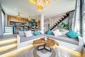 A modern living room with a sofa, coffee table, and staircase. - Tropical Blis Villa (Badung Regency)
