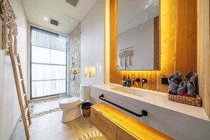 Un baño moderno con un espejo grande, tocador de madera y un inodoro.