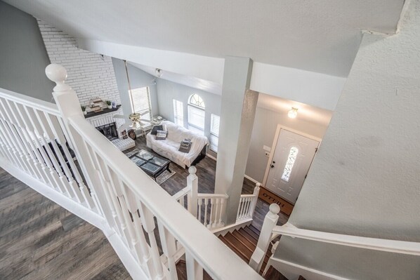 A spacious living area with a white staircase, a fireplace, and a door with a glass panel.