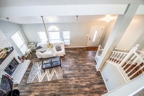 A spacious living area with a fireplace, a sofa set, a coffee table, and a staircase. - Deevine Homes - Private Bedroom with Shared Bathroom (2) (Carrollton)