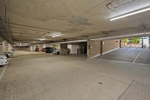 Eine mehrgeschossige Parkgarage mit Betonböden und -wänden, mehreren parkenden Autos und Deckenleuchten.