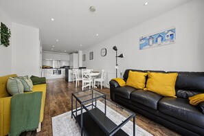 Ein modernes Wohnzimmer mit einem schwarzen Ledersofa, einem gelben Sessel und einem Glastisch.
