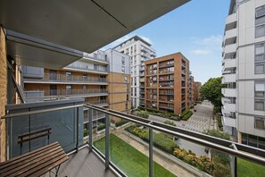 A multi-story residential building with balconies, a green lawn, and a clear sky. - Modern 2-Bed Flat with Balcony near Canary Wharf (London)