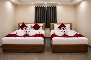 Een hotelkamer met twee bedden, elk voorzien van handdoeken gevouwen in hartvorm, rode kussens en een rode plaid.
