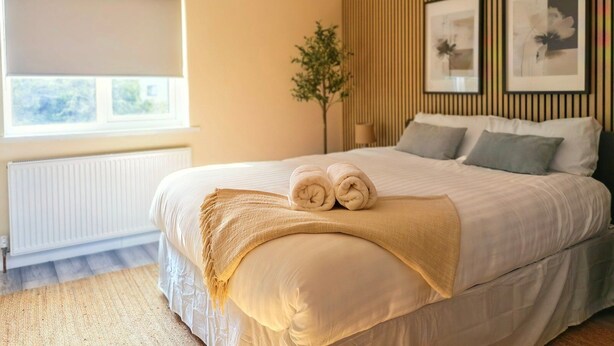 A bedroom with a bed, a window, a radiator, and a wall-mounted lamp. - Modern 2-Bed House Near Central Canals & Arena (Birmingham)