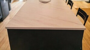 A modern dining area with a long table, chairs, and a kitchen area with a refrigerator. - Modern 2-Bed House Near Central Canals & Arena (Birmingham)