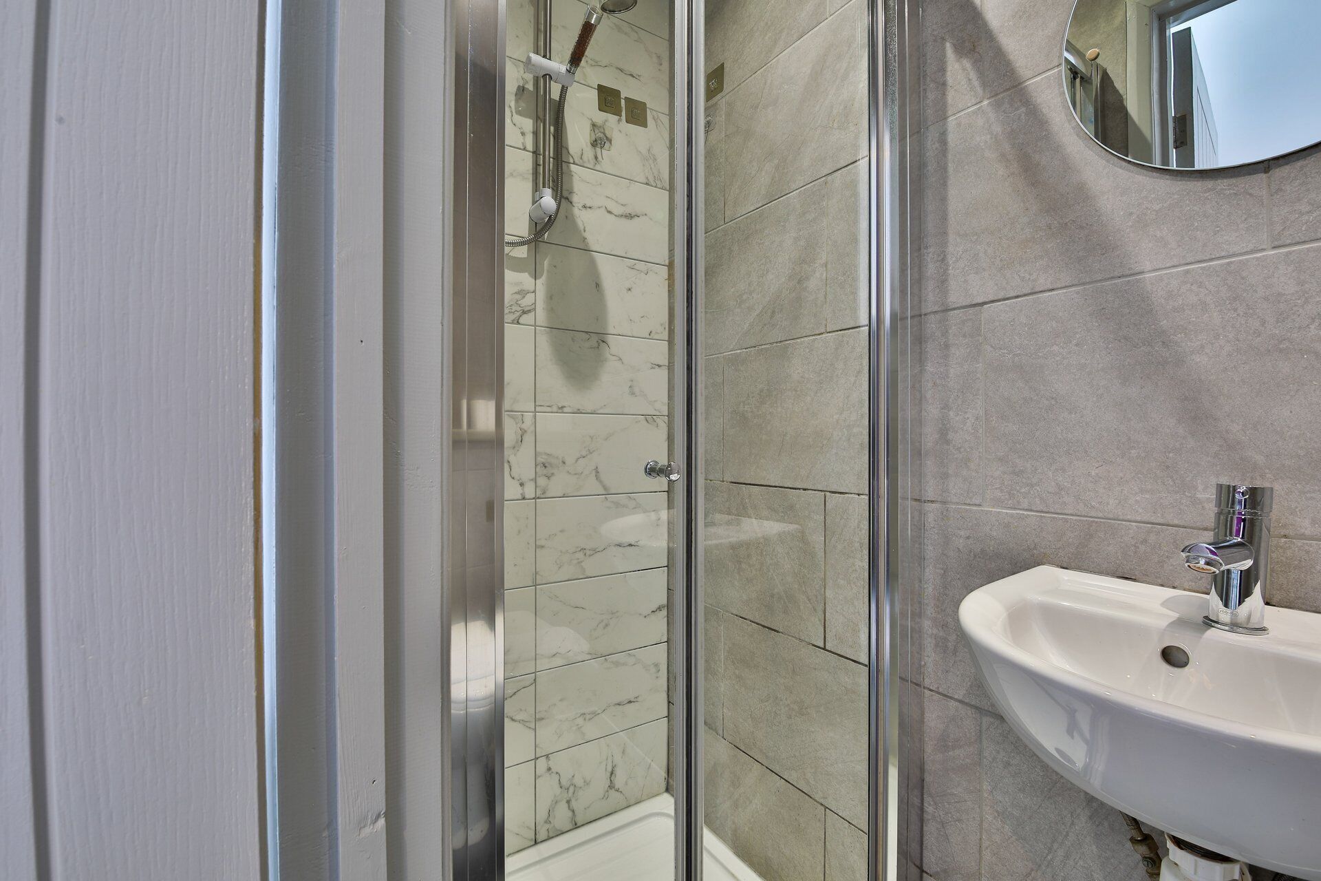 Un baño con cabina de ducha de vidrio, un lavamanos y un espejo.