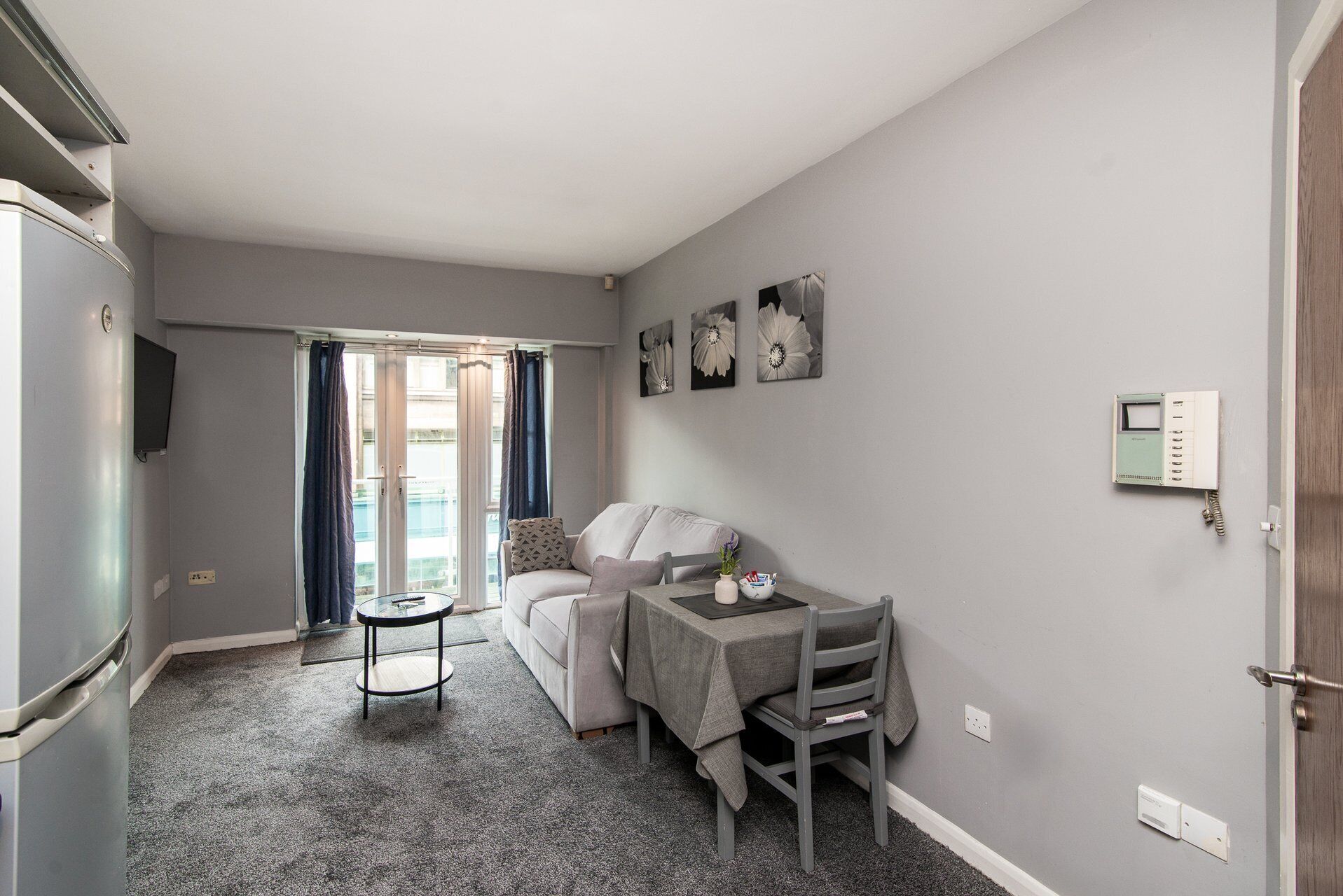 A compact living space with a kitchenette, a sofa, a dining table, and a small round table.