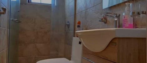 A bathroom with a toilet, a sink, and a shower area.