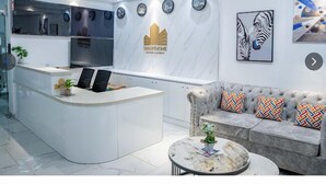 Una moderna recepción con mostrador de mármol, un sofá con cojines estampados y un reloj en la pared.