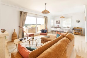 A spacious living room with a sofa, a dining table, and a view of the city. - La Manga Club Monte Verde Apartment 618 (Cartagena)